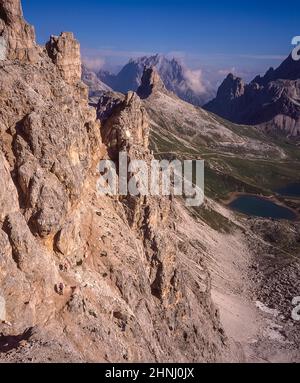 L'immagine è di un gruppo di arrampicatori che salgono lungo la via Ferrata protetta sul Paternkofel [Monte Paterno] guardando verso il pinnacolo del Toblinger Knoten Spitze vicino alle famose tre Torri, Conosciuto in tedesco come Drei Zinnen ma più poeticamente chiamato in italiano come le tre Cime di Laverado situato nella regione orientale di Sesto-Sesto delle Dolomiti italiane. Durante la prima guerra mondiale, l'esercito austriaco installò un cannone da campo sulla cima della piccola vetta, in modo che gli italiani si conchino a poco più di un chilometro di distanza. Gli arrampicatori sono in realtà sulla linea anteriore austriaca Foto Stock