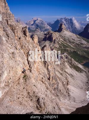 L'immagine è di un gruppo di arrampicatori che salgono lungo la via Ferrata protetta sul Paternkofel [Monte Paterno] guardando verso il pinnacolo del Toblinger Knoten Spitze vicino alle famose tre Torri, Conosciuto in tedesco come Drei Zinnen ma più poeticamente chiamato in italiano come le tre Cime di Laverado situato nella regione orientale di Sesto-Sesto delle Dolomiti italiane. Durante la prima guerra mondiale, l'esercito austriaco installò un cannone da campo sulla cima della piccola vetta, in modo che gli italiani si conchino a poco più di un chilometro di distanza. Gli arrampicatori sono in realtà sulla linea anteriore austriaca Foto Stock