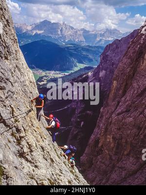 Questo gruppo di giovani adulti è in fase di avvicinamento finale al ponte che attraversa la gola sul tratto finale della Via ferrata Klettersteig Brigata Tridentina sentiero protetto che conduce al Rifugio Pisciadu nel Gruppo di montagne del Sella non lontano dal Passo Gardena-Groednerjoch Le Dolomiti italiane dell'Alto Adige. Foto Stock