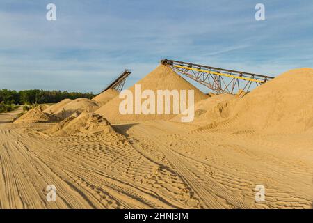 Montagne di sabbia e ghiaia e nastri trasportatori in una fossa di ghiaia. Pomerania, Polonia Foto Stock