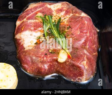 Carne di maiale fresca con aglio, rosmarino in confezione nera sottovuoto Foto Stock