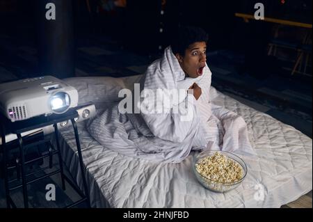 Ragazzo divertente che guarda l'orrore nascondersi sotto la coperta Foto Stock