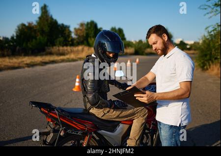 Studente maschile e istruttore, scuola di moto Foto Stock