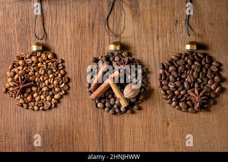 La collezione di spezie aromatiche e i diversi chicchi di caffè come le palle di Natale a forma di fila. Allspice, bastoncini di cannella, chiodi di garofano, fagioli arabica tostati alla noce moscata Foto Stock