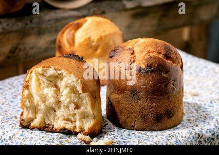 Pane di grano brioche tradizionale italiano fatto in casa con formaggio all'interno, intero e mezzo. In piedi sul tavolo da cucina con tovaglia floreale rustico. Primo piano Foto Stock