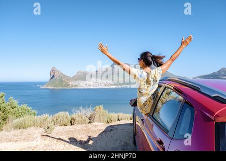 Donna fuori dal finestrino auto viaggio con mani in su, auto a Chapmans Peak Drive a Città del Capo Sud Africa guardando fuori l'oceano. Foto Stock