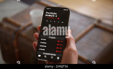 Telefono di tenuta della mano con l'app di commercio Mockup che osserva gli investimenti di valuta di Crypto che cadono in Euro Foto Stock
