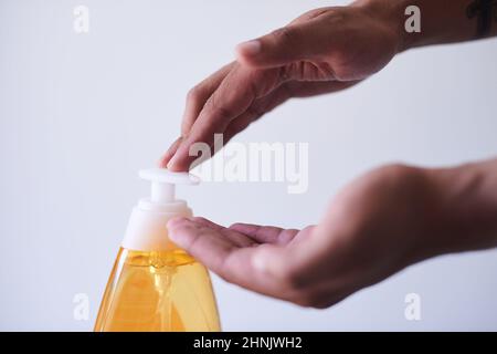 Un primo colpo di mani che erogano sapone con uno sfondo bianco Foto Stock