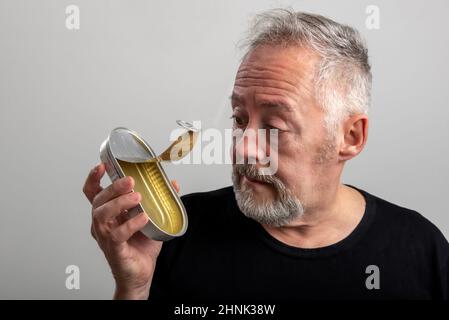 uomo preoccupato che tiene e guarda un vuoto sardine può Foto Stock