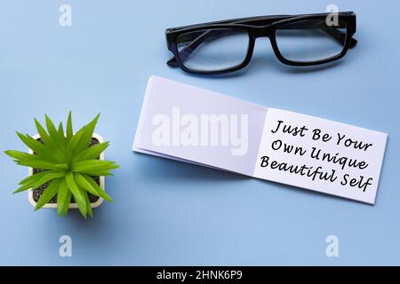 Citazione motivazionale su blocco note con occhiali da lettura e piante in vaso Foto Stock