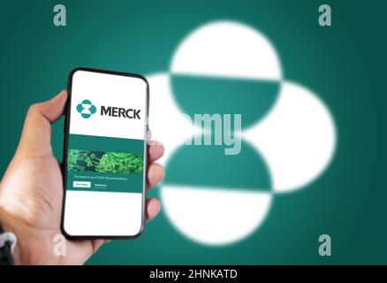 Una mano che tiene un telefono con l'app Merck Pharmaceutical Company sullo schermo Foto Stock