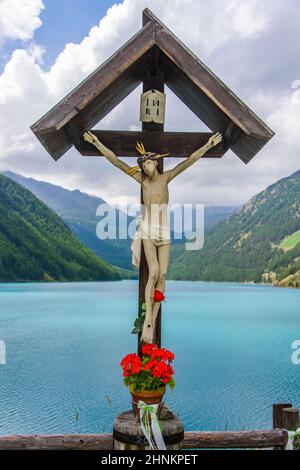 Crocifisso sulla riva del lago di Vernago in Val Senales, Alto Adige Foto Stock