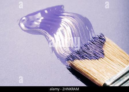 Pennello con vernice acrilica viola o viola su sfondo viola Foto Stock