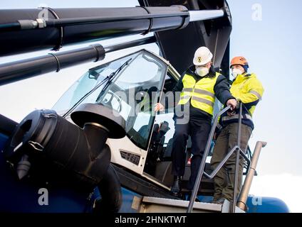 Cuxhaven, Germania. 17th Feb 2022. Stephan Weil (SPD), Presidente del Ministro della bassa Sassonia, esce da un cosiddetto reachstacker presso il terminal del BLUE Water BREB, mentre Steffen Rogalinsky, capo del terminal, gli si trova accanto. Il Presidente del Ministro Weil si informa sul sito della produzione e della movimentazione di componenti utilizzati per turbine eoliche offshore. Credit: Hauke-Christian Dittrich/dpa/Alamy Live News Foto Stock