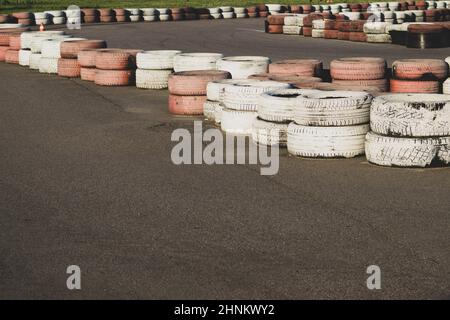 Barriera di sicurezza pista da corsa. Pista da corsa asfaltata con pneumatici rossi e bianchi. Stack di pneumatici colorati. Pista da karting Foto Stock