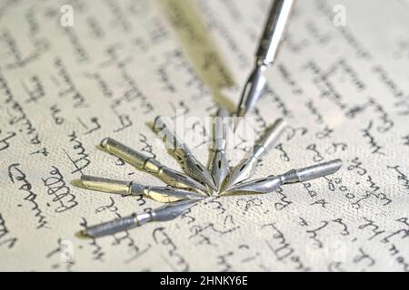 Primo piano di pennini metallici e vecchia penna sulla scrittura a mano vintage. Penna stilografica su un'antica lettera manoscritta. Vecchia storia. Stile retrò Foto Stock