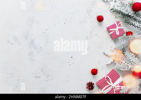 Natale, anno nuovo grigio calcestruzzo piatto. Vista dall'alto delle confezioni regalo a righe bianche rosse. Nastro regalo e carta da imballaggio. Abete di Natale, coni, Foto Stock