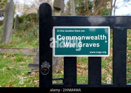 Un cartello su una porta del cimitero della chiesa che mostra che ci sono tombe di guerra del Commonwealth situato all'interno del cimitero Foto Stock