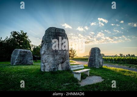 Tre rocce su prato verde con raggi del sole nel cielo Foto Stock