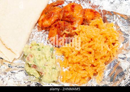 Gamberi piccanti su foglio accanto a tortillas di mais, riso e guacamole piegati Foto Stock