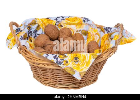 Un cestino di vimini con un tovagliolo pieno di noci isolato su uno sfondo bianco. Macro. Concetto di alimentazione sana. Foto Stock