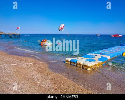 Parasailing in un cielo blu vicino spiaggia di mare. Il parasailing è un'attività ricreativa popolare tra i turisti in Turchia. Solo per uso editoriale. Foto Stock