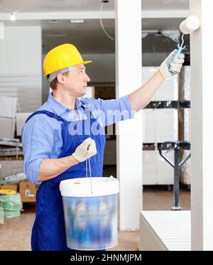 Professional lavoratore edile di innesco e pittura parete nella sala riparabili con rullo di verniciatura Foto Stock