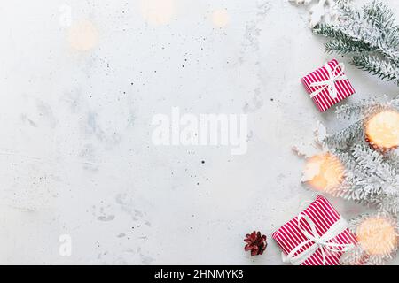 Natale, anno nuovo grigio calcestruzzo piatto. Vista dall'alto delle confezioni regalo a righe bianche rosse. Nastro regalo e carta da imballaggio. Abete di Natale, coni, Foto Stock