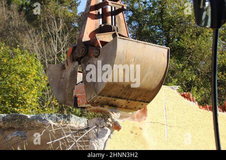 Caricamento di macerie da costruzione con un escavatore in un ambiente polveroso Foto Stock