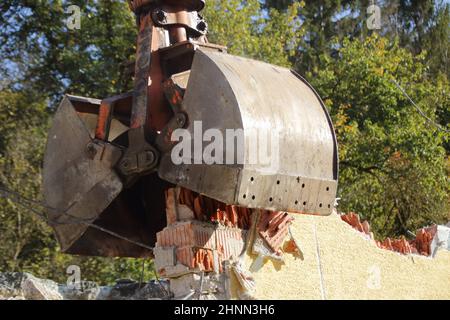 Caricamento di macerie da costruzione con un escavatore in un ambiente polveroso Foto Stock