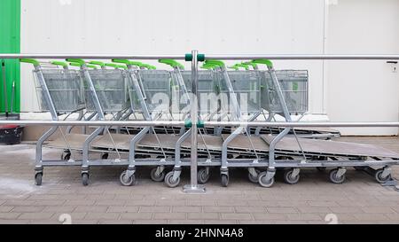 Molti carrelli in metallo sono parcheggiati in fila vicino a un supermercato all'aperto. Concetto di trading. Foto Stock