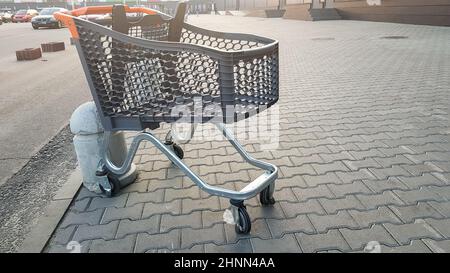 Carrello vuoto all'aperto vicino al supermercato. Solitudine, isolamento del carrello, quarantena, coronavirus. Un cestello di plastica vuoto su ruote con parti di plastica gialle lasciate sul marciapiede vicino al negozio. Foto Stock