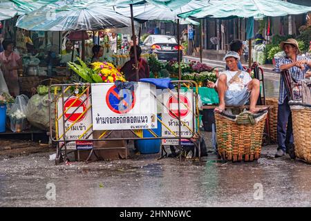 Gli uomini che hanno la prima colazione, un riposo e la vendita di rose al mercato dei fiori notturno Pak Klong Thalat a Bangkok Foto Stock