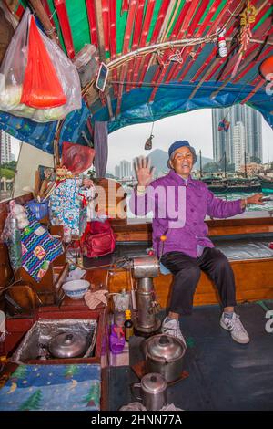 La vecchia donna offre la sua barca per i servizi di taxi nel porto di Aberdeen, Hong Kong Foto Stock