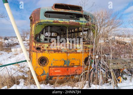 Autobus abbandonato arrugginito in campo innevato. Foto Stock