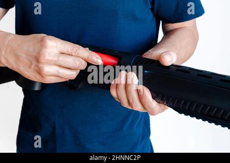 L'uomo carica il fucile con munizioni. Caricamento di un'arma con pompa a bore uniforme. Foto da primo piano. Foto Stock