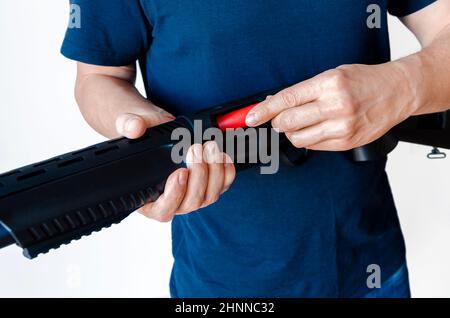 L'uomo carica il fucile con munizioni. Caricamento di un'arma con pompa a bore uniforme. Foto da primo piano. Foto Stock