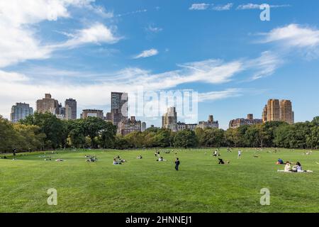 Le persone si rilassano di fronte agli alberi al Sheep Meadow Central Park a New York Foto Stock