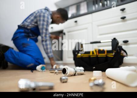 Fissaggio idraulico tubi da cucina. Servizio di infiltrazione dell'acqua Foto Stock