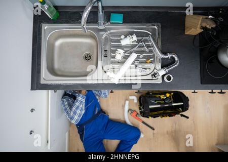 Fissaggio idraulico tubi da cucina. Servizio di infiltrazione dell'acqua Foto Stock