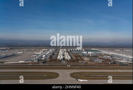 Vista aerea della torre di controllo del traffico aereo, edifici terminali principali, taxi e grembiule con diversi tipi di aerei di diverse compagnie aeree presso l'aeroporto di Monaco 'Frank Josef Strauss' Foto Stock