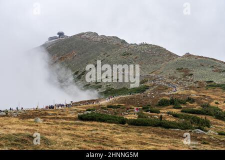 KARPACZ, POLONIA - 16 OTTOBRE 2021: I turisti salgono la popolare vetta della montagna polacca - Sniezka nelle montagne giganti in tempo nuvoloso. Foto Stock