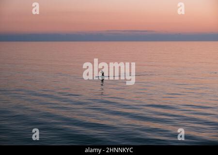 Uomo in canoa in mezzo al mare Foto Stock