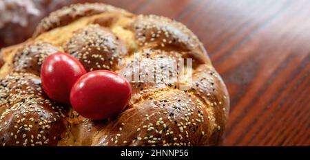 Tsoureki greco, pane dolce pasquale, cozonac e uovo rosso tintura su un tavolo di legno vista ravvicinata. Brioche intrecciata, dessert tradizionale festivo Foto Stock