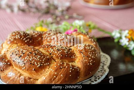 Pane dolce pasquale, cozonac o tsoureki a tavola, vista ravvicinata dall'alto. Brioche intrecciata, sfida tradizionale festosa e decorazione floreale Foto Stock
