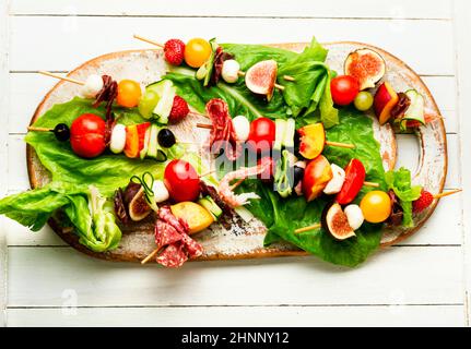 Antipasto di gamberetti, jamon, frutta e verdure su spiedini di legno.piatto Lay Foto Stock