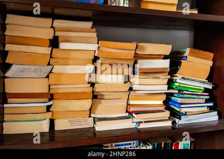 Vecchi libri gialli impilati sullo scaffale in libreria. Foto Stock