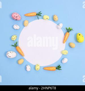Carta di Pasqua carta carta spazio copia con uova e carote su sfondo blu pastello chiaro. Disposizione piatta minima. Organizzazione creativa delle vacanze di primavera Foto Stock