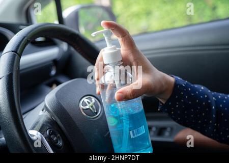 Bangkok, Thailandia, 1 luglio 2021 New Normal, Asian Working Woman lavando mano da press blu alcol sanitizzante gel per proteggere la sicurezza Coronavirus in auto. Foto Stock