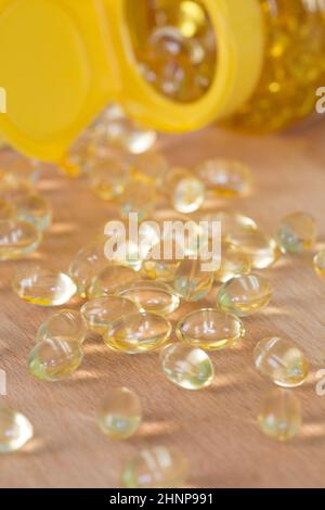 Pillole di omega di olio di pesce versato da una bottiglia di plastica di apothecary. Foto Stock
